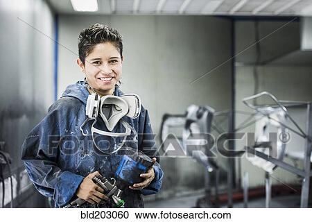 Stock Image - Worker smiling in manufacturing plant. Fotosearch