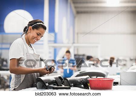Stock Image - Worker smiling in manufacturing plant. Fotosearch