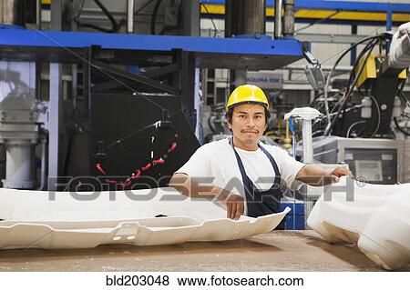 Stock Photo - Worker smiling in manufacturing plant. Fotosearch