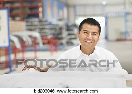 Stock Photograph - Worker smiling in manufacturing plant. Fotosearch