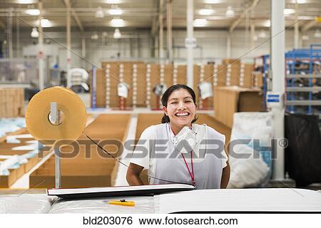 Stock Photograph - Worker smiling in manufacturing plant. Fotosearch
