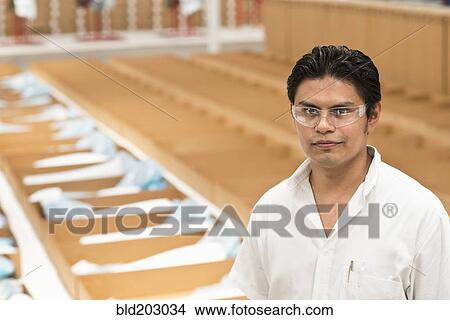 Picture - Worker standing in manufacturing plant. Fotosearch