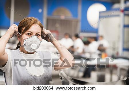 Picture - Worker wearing face mask in manufacturing plant. Fotosearch