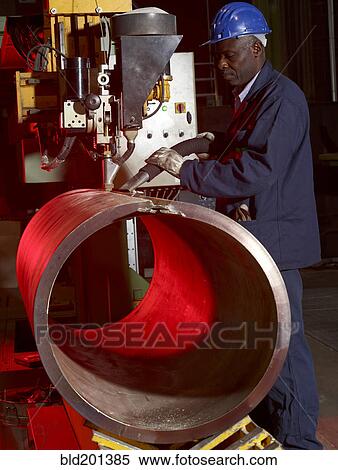 Stock Photography - Worker working on steel pipe in factory. Fotosearch