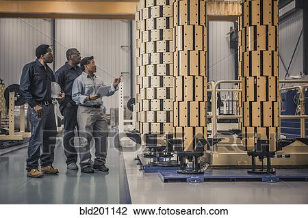 Stock Image - Workers looking at equipment in factory. Fotosearch
