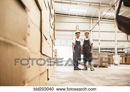 Stock Image - Workers standing in manufacturing plant. Fotosearch