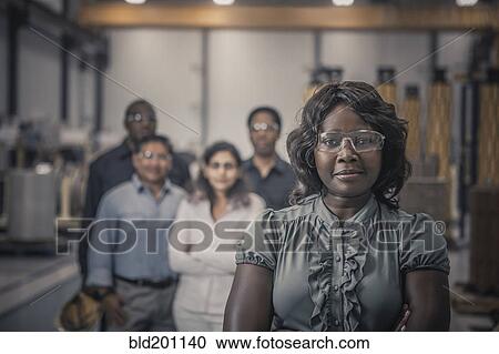 Stock Image - Workers standing together in factory. Fotosearch
