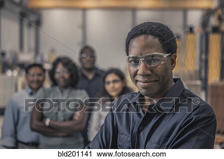 Stock Image - Workers standing together in factory. Fotosearch