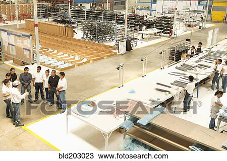 Stock Image - Workers talking in manufacturing plant. Fotosearch