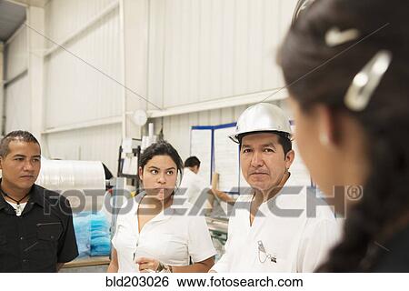 Stock Photograph - Workers talking in manufacturing plant. Fotosearch