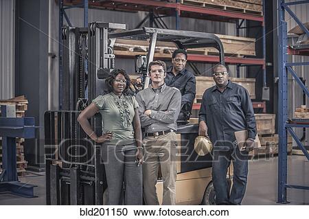 Stock Image - Workers with forklift in factory. Fotosearch