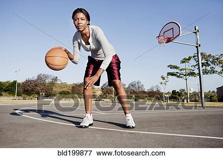 Stock Photo - Young woman playing basketball. Fotosearch