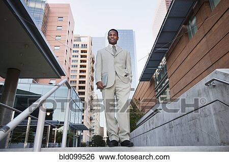 Stock Photograph - African American businessman standing at top of stairs. Fotosearch