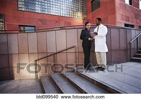 Stock Image - African American doctor and businesswoman using digital tablet. Fotosearch