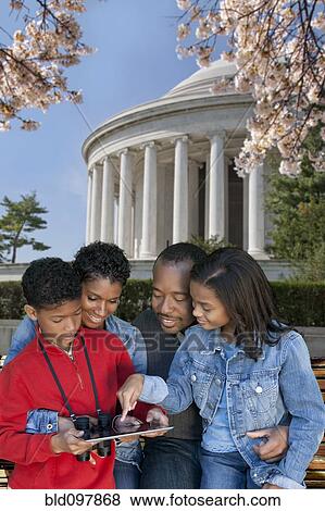 Stock Photo - African American family using digital tablet on vacation. Fotosearch