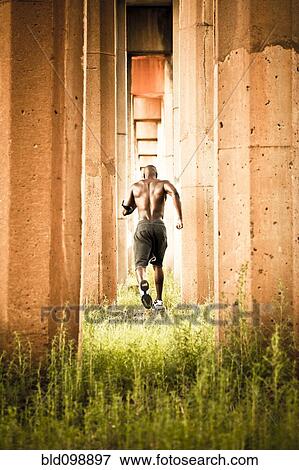 Stock Photo - African American man jogging between pillars. Fotosearch