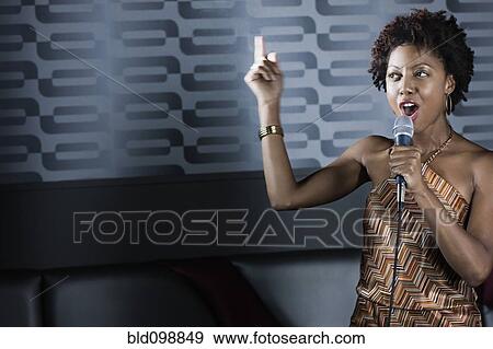 Stock Photo - African American woman singing karaoke in nightclub. Fotosearch