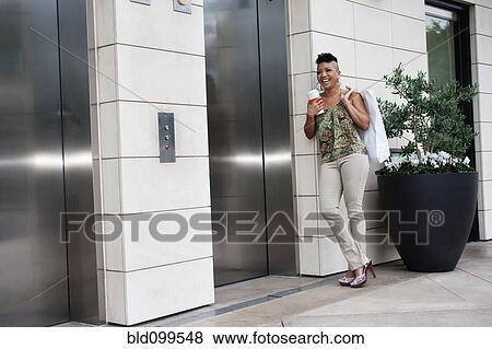 Stock Photo - Asian woman with shopping bag waiting for elevator. Fotosearch