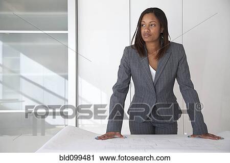 Stock Image - Black architect reviewing blueprints in office. Fotosearch