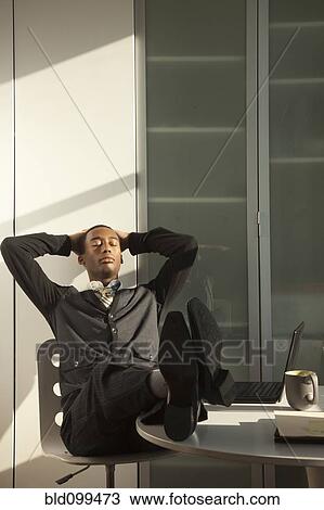 Black businessman sitting at desk with feet up View Large Photo Image Stock Image - Black businessman sitting at desk with feet up. Fotosearch