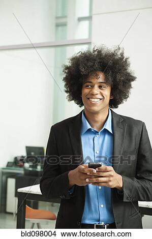 Picture - Black businessman text messaging on cell phone. Fotosearch
