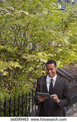 Black businessman using digital tablet outdoors View Large Photo Image Stock Image - Black businessman using digital tablet outdoors. Fotosearch