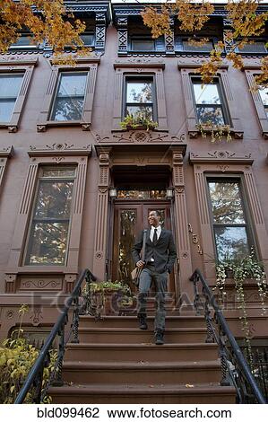 Stock Image - Black businessman walking down front stoop steps. Fotosearch