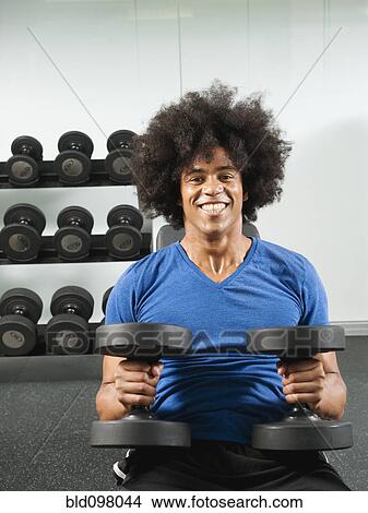 Picture - Black man lifting dumbbells in gym. Fotosearch