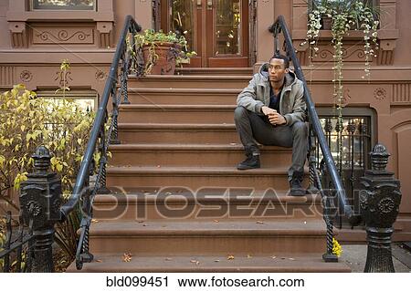 Stock Image - Black man sitting on front stoop. Fotosearch
