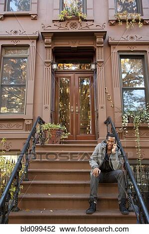 Stock Image - Black man sitting on front stoop. Fotosearch