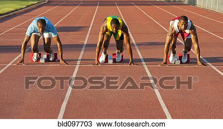 Stock Image - Black runners at starting block in race. Fotosearch