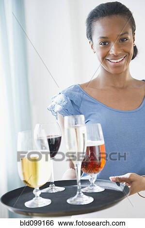 Stock Photograph - Black waitress carrying tray of drinks. Fotosearch