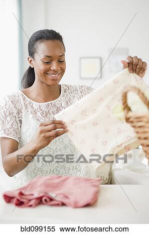 Stock Photography - Black woman folding laundry. Fotosearch