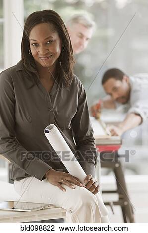 Stock Image - Black woman holding blueprints. Fotosearch