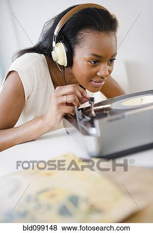 Stock Photo - Black woman listening to record player. Fotosearch