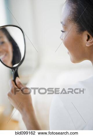 Stock Image - Black woman looking in mirror. Fotosearch