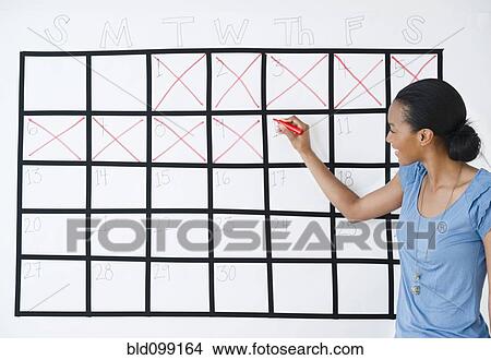 Picture - Black woman marking the days off calendar. Fotosearch