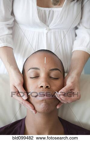 Stock Image - Black woman receiving acupuncture treatments. Fotosearch
