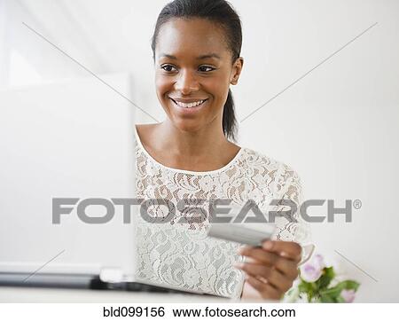 Stock Photograph - Black woman shopping online with credit card. Fotosearch