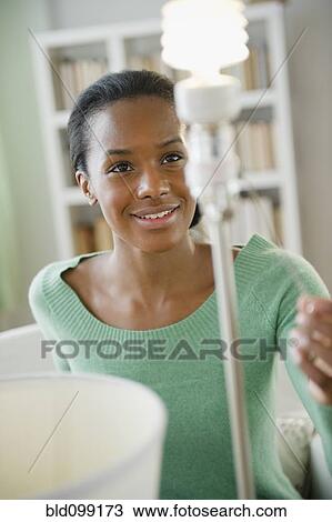 Stock Image - Black woman turning on CFL light bulb. Fotosearch