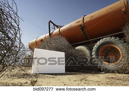 Stock Photo - Blank placard next to abandoned tanker truck. Fotosearch