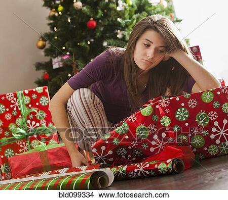 Picture - Bored Caucasian woman wrapping Christmas gifts. Fotosearch