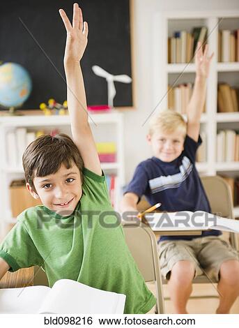 Stock Photograph - Boys in classroom raising hands. Fotosearch