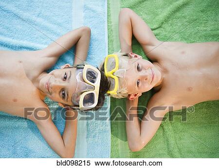 Stock Photography - Boys laying on towels wearing swim goggles. Fotosearch