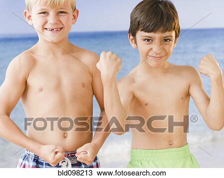 Stock Image - Boys on beach flexing biceps muscles. Fotosearch