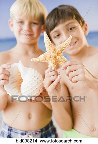 Picture - Boys on beach holding seashells. Fotosearch