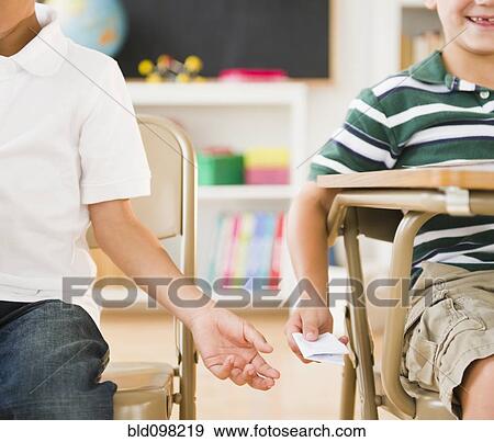 Stock Photo - Boys passing note in classroom. Fotosearch