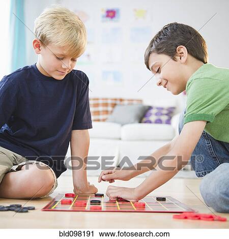Stock Image - Boys sitting on floor playing checkers. Fotosearch
