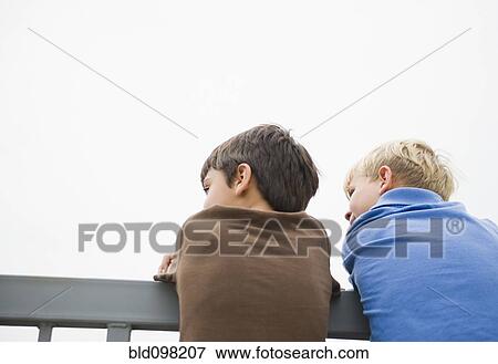 Stock Photo - Boys standing looking over railing. Fotosearch