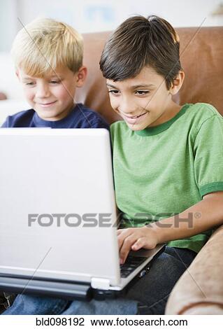 Stock Image - Boys using laptop together. Fotosearch